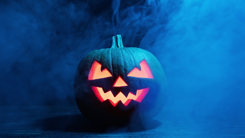Halloween pumpkin glowing inside in the dark. Scary Pumpkin with smoke around it. Pumpkin glows on Halloween night. Close-up in 4K, UHD Royalty-Free Stock Footage #1095367741