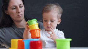 Happy cute family at home. Child collects colored cubes. Mom with her baby son play with toys at home. Happy family concept. Parent helps son in learning. Preschool family education. Mom and baby play - Powered by Shutterstock - Get 15% off with code: PIKWIZARD15
