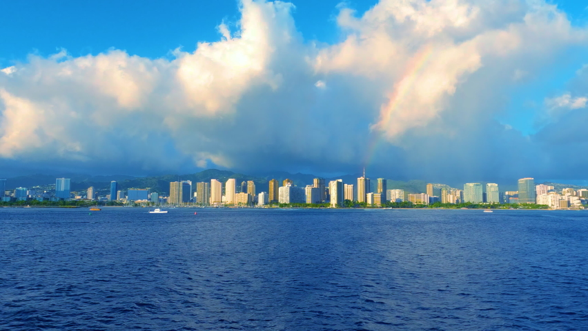 Rainbow over Honolulu city. Town from the ocean. Tall buildings on Waikiki Beach in Oahu. Skyscrapers on Hawaiian shoreline. Shoreline of Hawaiian island. Cityscape along the tropical island.