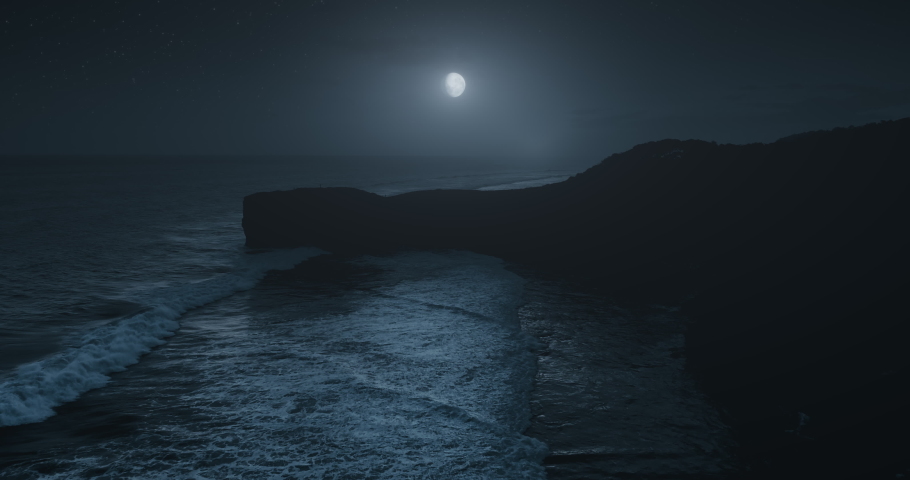 Moonlight above ocean waves washing rock shore aerial view. Close up mountain silhouette on moon and stars light night sky background. Atmospheric Halloween concept. Travel Los Angeles, California USA Royalty-Free Stock Footage #1095380673