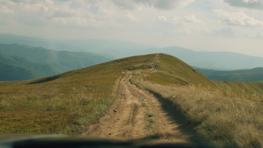 Descent by car along a trodden path on a beautiful grass hill. Amazing landscape of foggy mountains, spending leisure time outdoor. First person view. Slow motion.