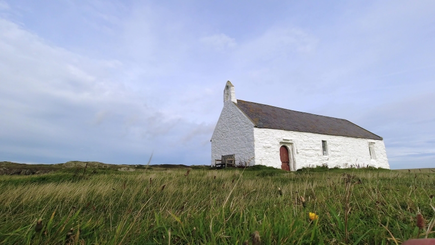 St Cwyfan landmark white church on windy grassy Anglesey Porth Cwyfan coast