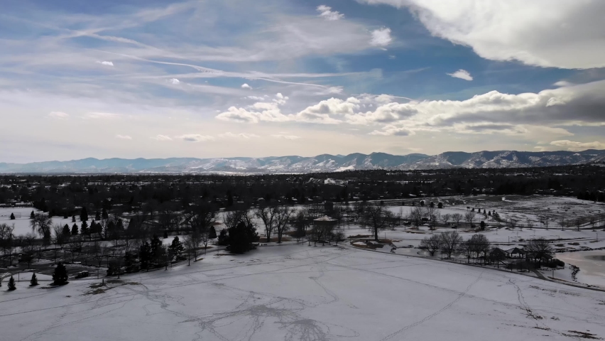 Rocky Mountains with Cloudy Skies on Beautiful Day • Snow Covered Park in Western Metro Denver • Slow Aerial Drone Shot • HD Horizontal
