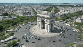 Triumphal arch and car traffic on roundabout with Paris cityscape, France. Aerial orbiting