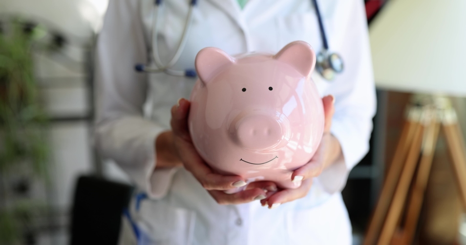 Female nurse doctor with stethoscope holding pink piggy bank Royalty-Free Stock Footage #1095396579