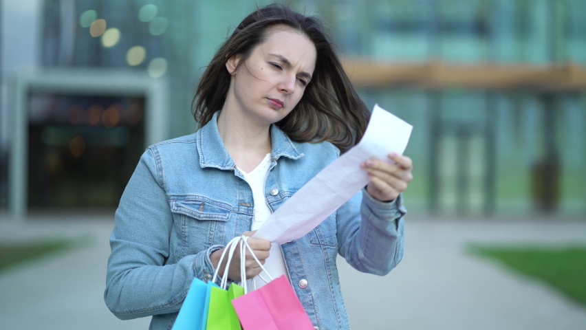 A girl with a cash receipt in her hands on the background of a shopping center after shopping Royalty-Free Stock Footage #1095404495