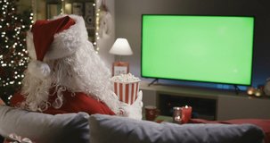 Santa Claus relaxing on the couch and watching movies at Christmas, he is eating popcorn