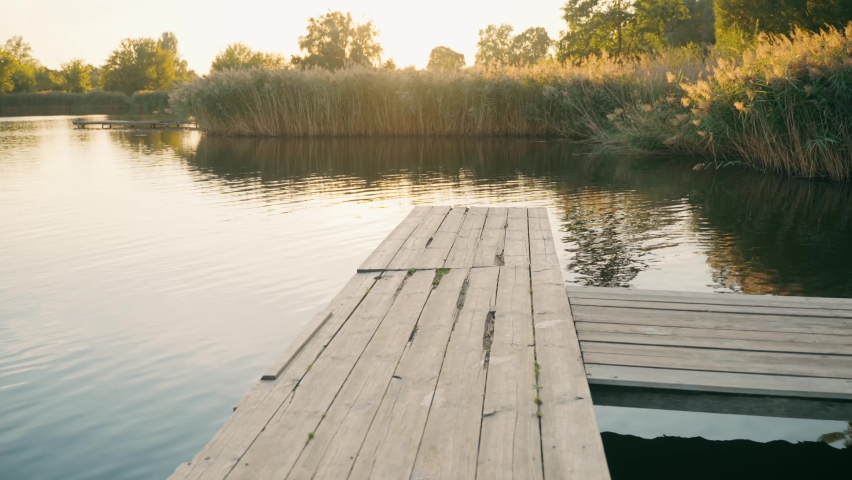 Three guys jump from a tree pier into a lake.