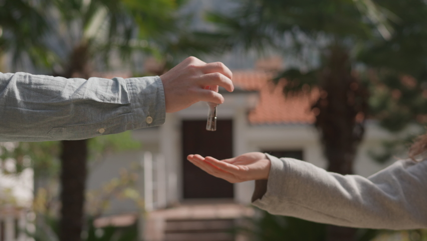 Close up Asian American female hand passing key male outdoors sunlight. Woman handing keys new house man customer. Buying dwelling. Selling home. Real-estate agent job. Handing over keys young couple. Royalty-Free Stock Footage #1095408751