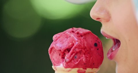 Beautiful woman eating ice cream in the park, close up. Slow motion. Young attractive woman in white hat enjoying tasty ice cream in the green sunny summer outdoors. 4K, DCi.  Stock Video