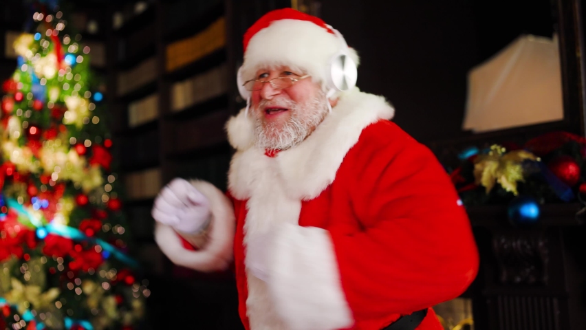 Santa Claus uses headphones to listen to music and dances in a great mood on Christmas Eve. Royalty-Free Stock Footage #1095414757
