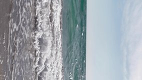 Vertical Video, Beautiful sea waves on a summer sunny day on the sandy beach. Close-up, no people. Super slow motion.