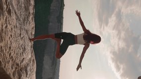 Vertical Video, Athletic Woman Performs Spiritual Yoga Pose on Mountain Top Sunset. Healthy Lifestyle and Zen. Slim Girl Goes in for Sports Outdoors in Beautiful Natural Place. Freedom, Slow Motion