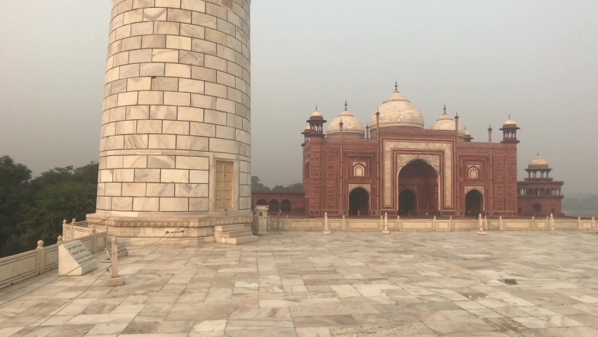 Agra, India, November 2019 - A large brick building with a tower in the background
