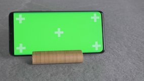 vertical video. phone with green background stand on a wooden stand