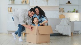 Multiracial multiethnic mother and father Indian Hispanic Caucasian parents push cardboard boxes with little cute child girl daughter ride inside homeowners family playing fun in new house relocation - Powered by Shutterstock - Get 15% off with code: PIKWIZARD15