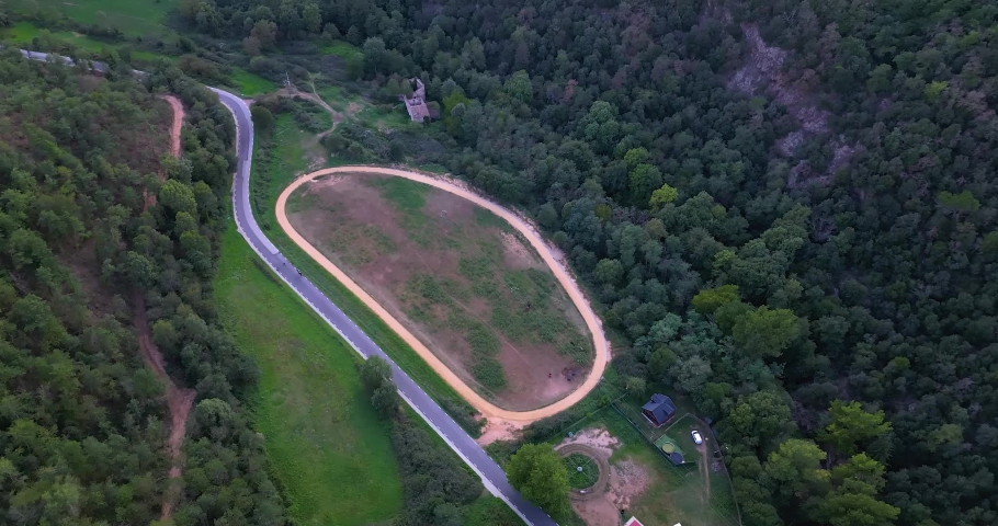 views from the air of horse facilities with stables, horse walkers, wooden house, hippodrome and road