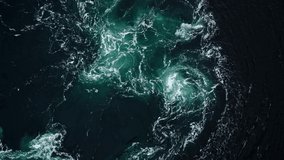 4K drone video with birds-eye view of the abstract and powerful water currents, rapids and whirlpools of the worlds larges maelstrom Saltstraumen, Norway.