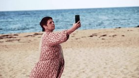 Woman in her 60s taking a selfie on the beach.