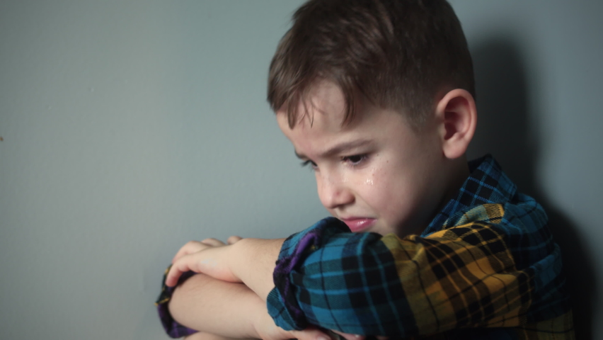 Portrait of a Cute boy with big tears running down his cheeks, Sad upset boy sitting in corner lifestyle.Child punished sitting crying in the corner. Domestic violence concept. Child abuse | Shutterstock HD Video #1095422215