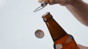 Closeup man hand opening beer glass bottle with opener in super slow motion. Bubbling foam raising up from dark bottleneck on white background. Fizzy lager alcohol beverage foaming. Party concept - Powered by Shutterstock - Get 15% off with code: PIKWIZARD15