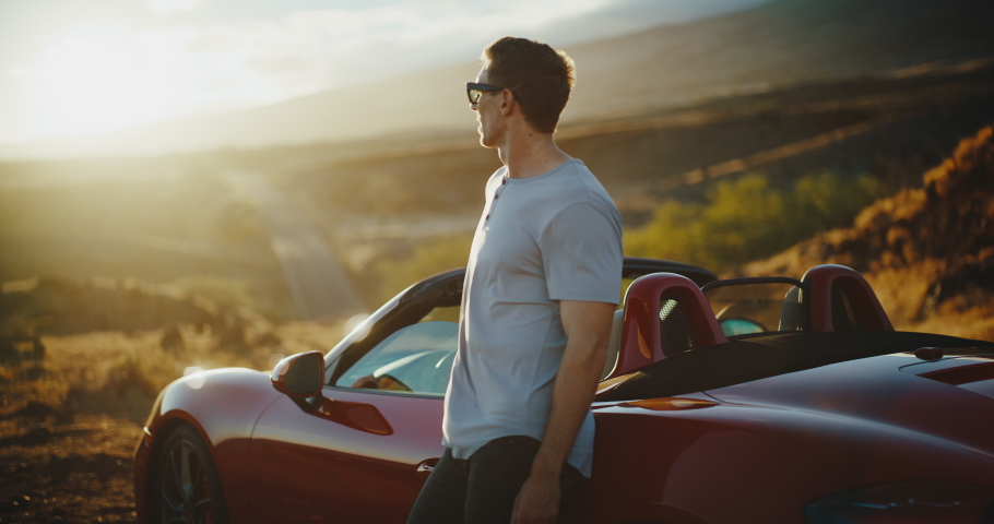Successful young man watching the sunset on epic road trip in classic convertible sports car Royalty-Free Stock Footage #1095424703