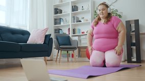 Comic overweight woman exercising home, watching fitness tutorial on laptop
