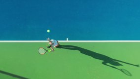 4K aerial top-down view of a young female sportsman during her practice. A close-up of a girl athlete serves the tennis ball. Young woman is hitting the ball with her tennis racket at sunset - Powered by Shutterstock - Get 15% off with code: PIKWIZARD15