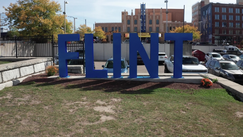 Flint, Michigan blue city sign with drone video pulling out and up.