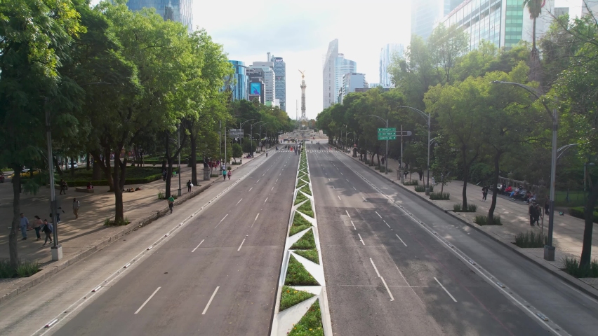 drone shot in reverse of a sunset on the avenue of paseo de la reforma in mexico city completely empty with a view of the angel of independence