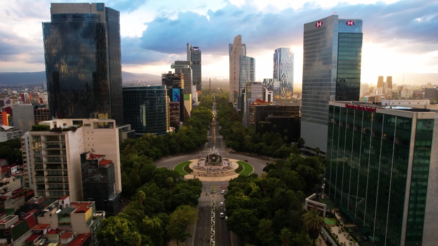 drone shot in reverse of a sunset on the paseo de la reforma in mexico city with a view of the large buildings