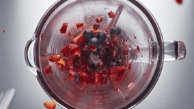 Juicy tasty strawberry blueberry pomegranate falling blender bowl in super slow motion close up. Electric mixer blending fresh organic berries top view. Preparing vitamin healthy sweet smoothie. - Powered by Shutterstock - Get 15% off with code: PIKWIZARD15