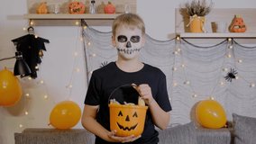 Boy in skeleton makeup holds a bucket of candy. The child celebrates Halloween - Powered by Shutterstock - Get 15% off with code: PIKWIZARD15