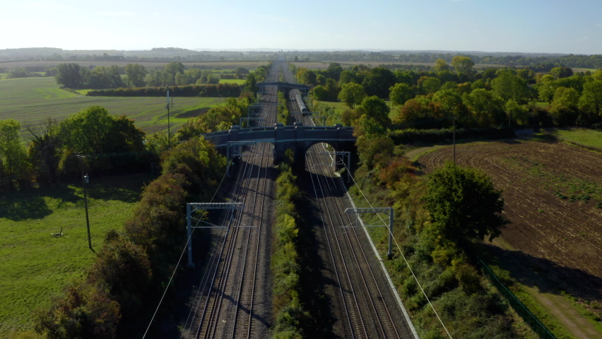 Train travelling at high-speed Drone view. Aerial shot of a fast passenger train in the UK countryside. Speed Passenger train to London. A high-speed red electric train.  Royalty-Free Stock Footage #1095440493