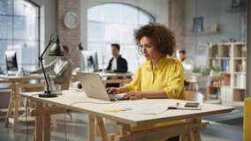 Portrait of Biracial Productive Young Woman Working on Computer in Modern Busy Office. Female Team Lead Smiling After Fulfilling an Important Task. People Working in the Background. Zoom In Shot. - Powered by Shutterstock - Get 15% off with code: PIKWIZARD15