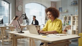 Portrait of Biracial Active Young Woman Working on Laptop in Busy Office. Female Collaborating with Team Online, Smiling, and using a Phone. People Using Computers in the Background. Time Lapse Shot. - Powered by Shutterstock - Get 15% off with code: PIKWIZARD15