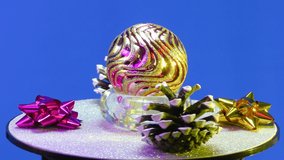 On a blue background, Christmas decorations rotate on a silver chroma key stand
