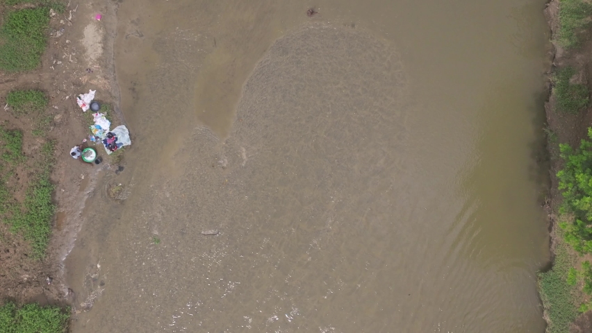 Haitian women washing clothes in waters of Massacre River at border between Haiti and Dominican Republic. Aerial top-down forward directly above
