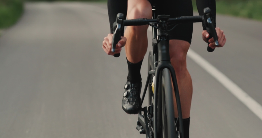 Man cyclist riding on road bike on the road training for a triathlon. Cyclist twisting pedals, cycling on the highway having healthy activity, preparing for a marathon | Shutterstock HD Video #1095457647