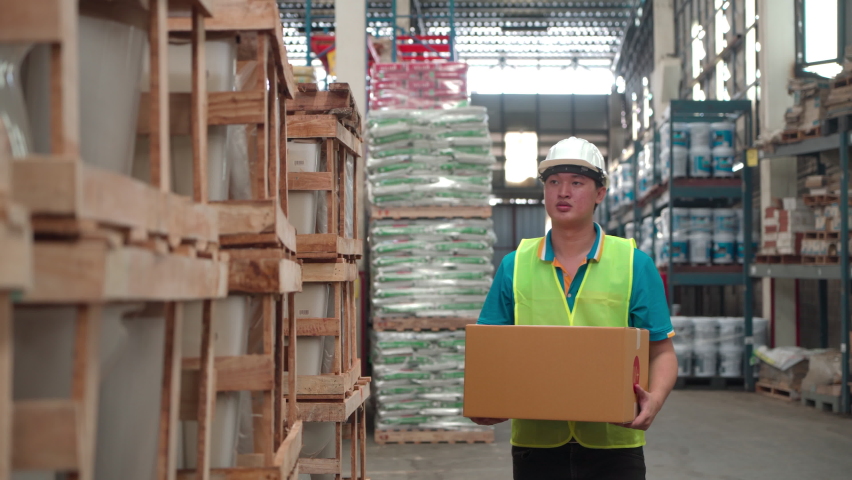 Asian worker gets backache painful while lift heavy cardboard box to wooden shelf in warehouse store, caucasian chief co-worker helps him to medical care clinic, health insurance for staff concept Royalty-Free Stock Footage #1095471657