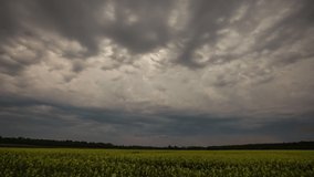 Dark stormy clouds moving over spring field. Time lapse for time passing concept