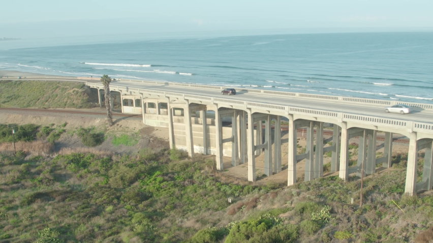San Diego California coast highway bridge ocean aerial pan over and around highway medium angle at sunset