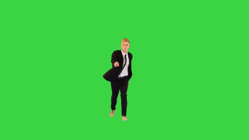 Witty guy in black office suit performs funny dance and sits on a twine in the end on a Green Screen, Chroma Key.