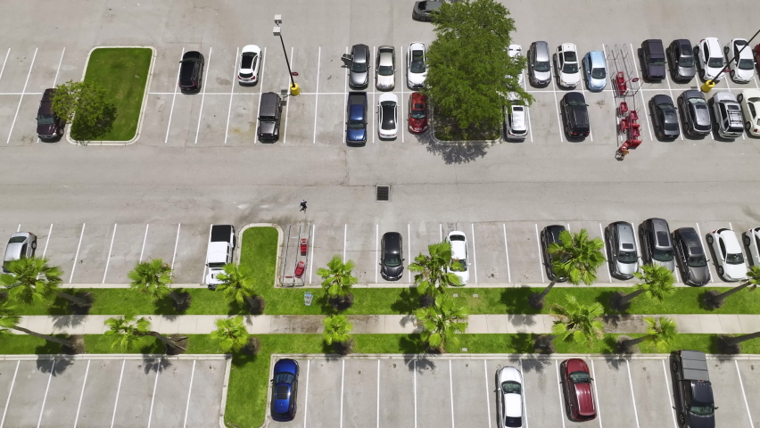 Aerial view of many colorful cars parked on parking lot with lines and markings for parking places and directions