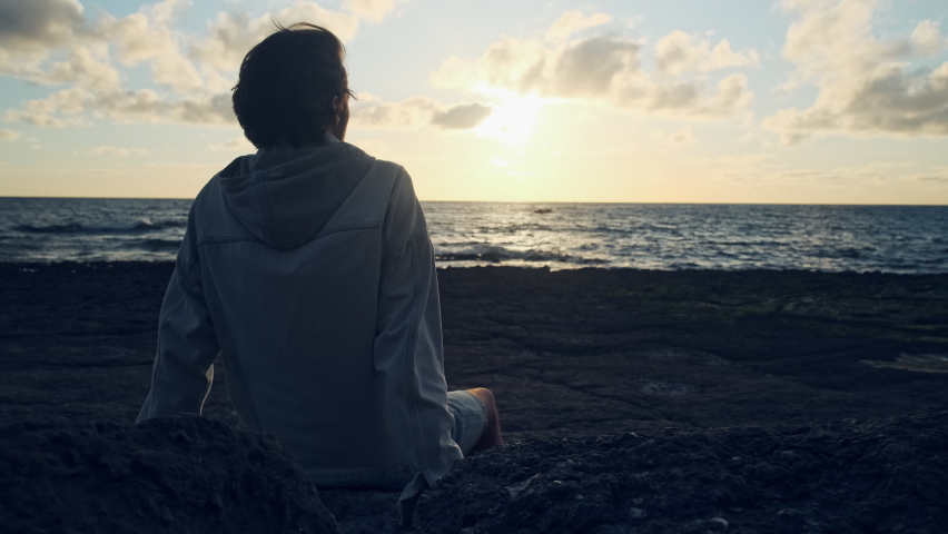 Human looks to the sun over horizon while sunrise. Man on a beach is looking distance during  summer sunset.  Person contemplates the beauty of nature. Freedom. Slow motion. Cinematic dramatic look. Royalty-Free Stock Footage #1095495061