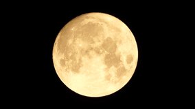 A glowing golden huge full moon seen from earth through the atmosphere against a starry night sky. A large full moon moves across the sky, the moon moving from the left frame to the right. - Powered by Shutterstock - Get 15% off with code: PIKWIZARD15