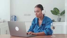 Social distancing and self care: Multitasking young Asian woman, in wireless headphones, teleconferencing from home. Overworked and busy freelancer using laptop, works on new project. Telecommute