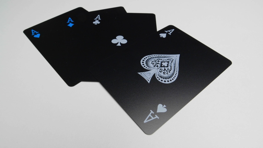 Orbit shot of the four aces on a white surface of a deck of black cards