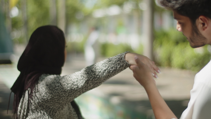 Close-up of muslim man kissing his womans hand outdoors while walking in park. Dark-haired guy showing affection, spending time with pretty Arabian girl in hijab. Courtship, ethnicity concept. Royalty-Free Stock Footage #1095511399