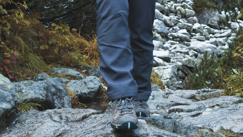 Travel on mountain trails.  Footwear for outdoor activities. Walking across mountain streams. Hiking. Traveling through the mountains. The camera follows the hiker's feet. Royalty-Free Stock Footage #1095512857